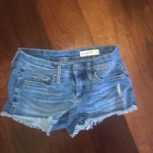 Denim shorts with distressed bottoms.
